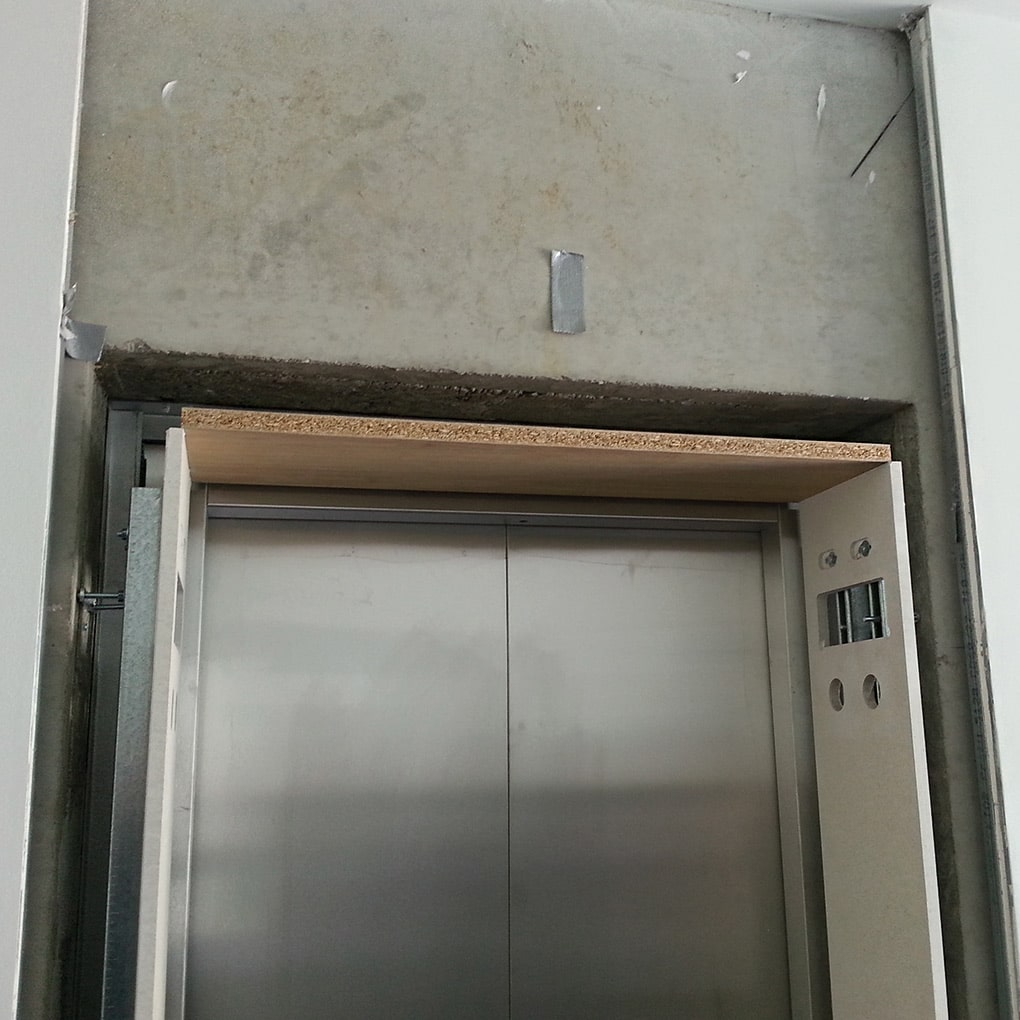 eine Rohbaufläche über einer Fahrstuhltür in Vorbereitung der Wandverkleidungen montieren
