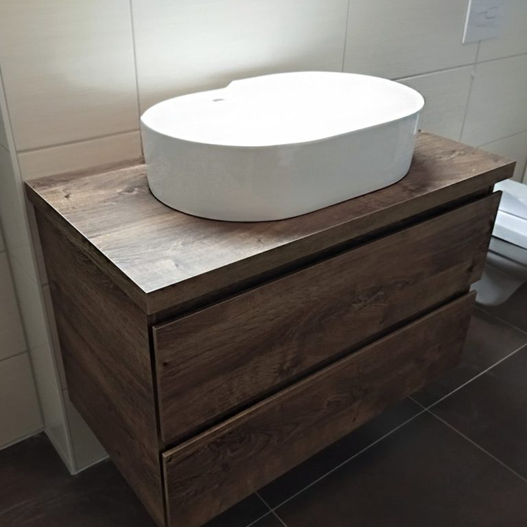 ovales weißes waschbecken auf hochwertigem holzschrank im Bad montiert